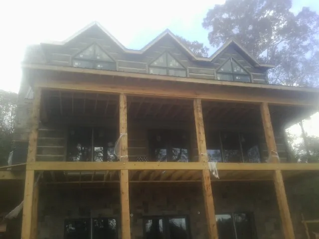 Dormers and porch framing on a large log home under construction — Roof Coating work by our crew in Montague