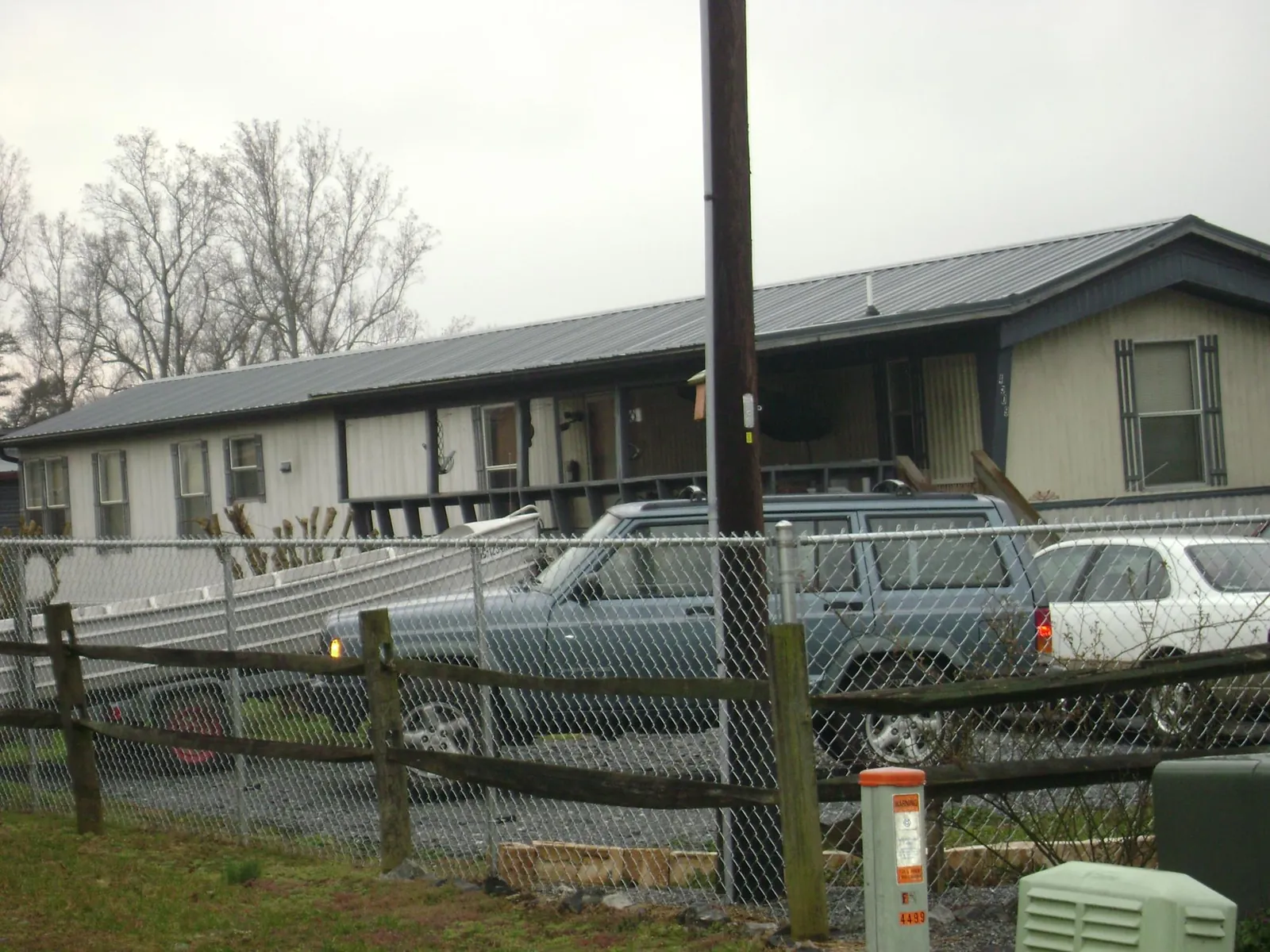 Dark metal roof on a long single story building behind a chain link fence in Montague