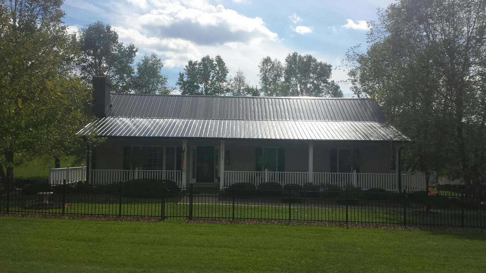 Gray metal roof on a brick ranch with a full width front porch — Gutter Guard Installation work by our crew in Montague